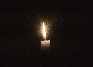 Image is of a single candle signifiying pregnancy and infant loss remembrance