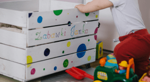 Toddler places toys in bin